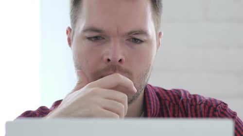 Pensive Young Man Thinking and Working on Laptop Front Close Up