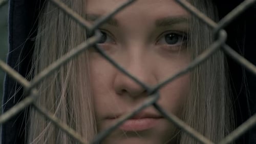 Worried Teenager Behind a Chain-Link Fence