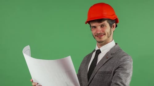 Glücklicher Architekt untersucht seine Blaupausen und lächelt freudig