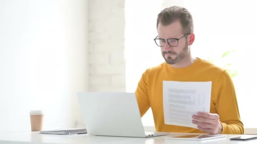Adult Working with Laptop and Documents in Office