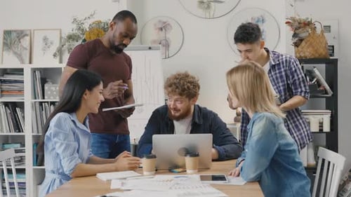 Diverse Team Collaborating on Laptop in Modern Office