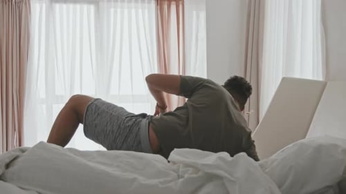 Homme latin s'étirant dans son lit après le sommeil