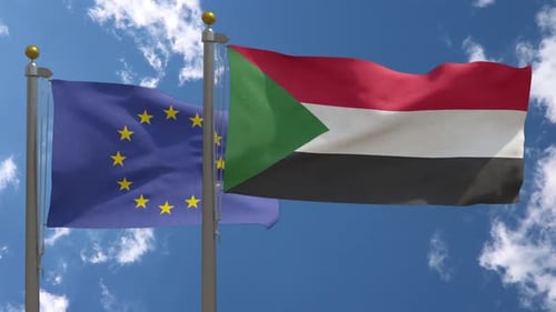 European Union and Sudan Flags Waving Against Blue Sky
