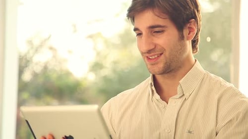 Smiling Man Uses Tablet Indoors