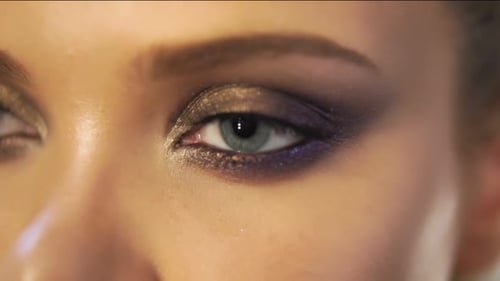 Vue rapprochée des yeux d'une femme avec un magnifique maquillage doré s'ouvrant au ralenti