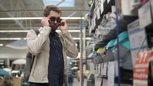 Young Man is Trying on a Swimming Goggles in a Big Store of Goods for Sport