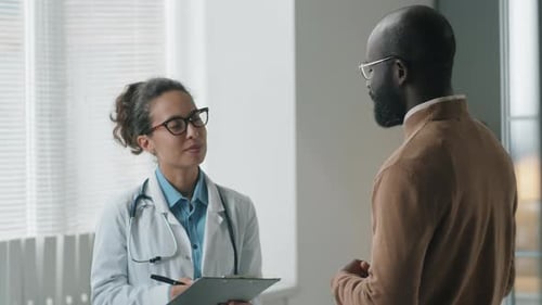 Female Doctor Talking with African American Patient in Clinic