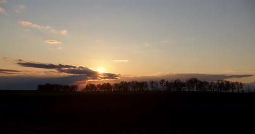 Crépuscule. Coucher de soleil sur fond d'arbres. Timelapse des nuages
