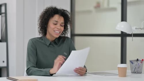 Woman Celebrates Good News in Office Reading Documents