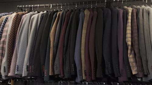 Camera Shows Colorful Male Suits in Row in a Hanger. Shop Jacket Men Series, Business Hanger