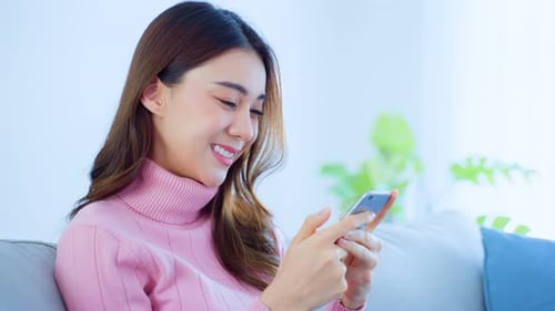 Woman Smiling Using Her Mobile Phone at Home
