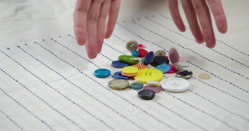 Colorful Buttons Falling on Striped Fabric Closeup