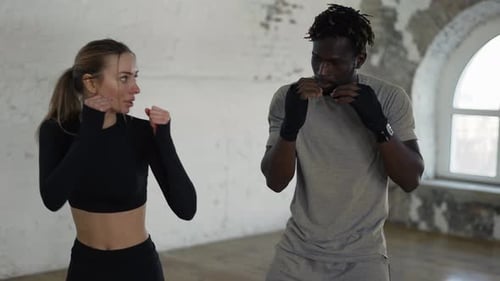 Woman Practices Boxing With a Trainer in Gym