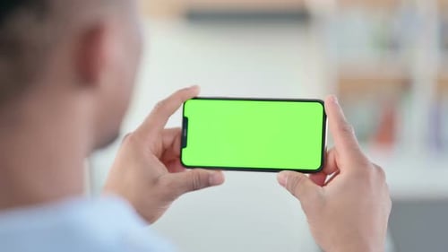 African Man Watching Smartphone with Green Chroma Key Screen