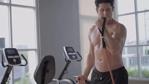 Fit Man Exercises with Resistance Band in Gym
