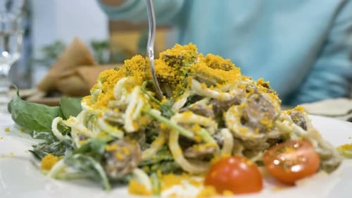 Person Winds Pasta on Fork From Dish of Vegetables and Yolk