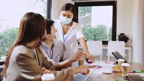 Young people with face masks back at work in office after lockdown