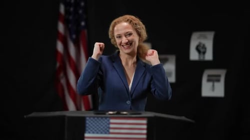 Smiling Woman at Podium Celebrating Victory with Gestures