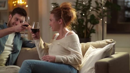 Happy Couple Drinking Red Wine at Home in Evening