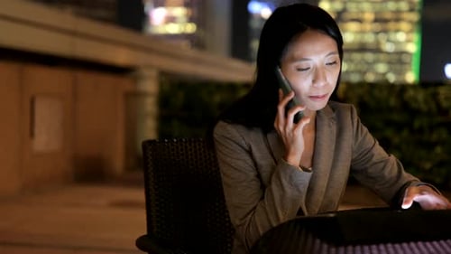 Woman Uses Tablet and Phone at Night in City