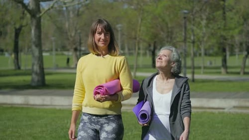 Front View of Women in Park Holding Yoga Mat in Hands, Talking
