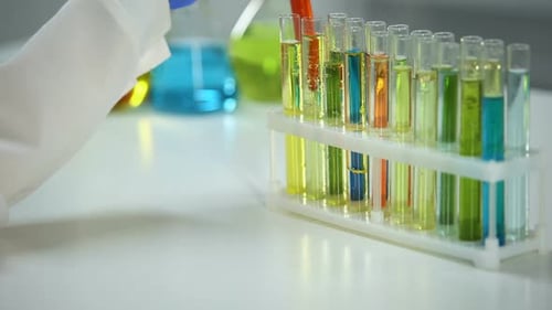 Chimiste vérifiant le tube avec liquide orange, agent colorant, substance de lavage
