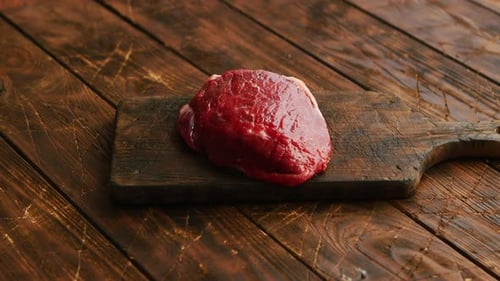Big Fresh Piece of Meat Laid on Wooden Cutting Board
