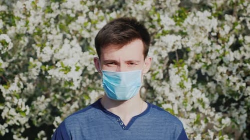 A Man in a Gauze Bandage Against a Background of Flowering Trees. Allergy During the Spring