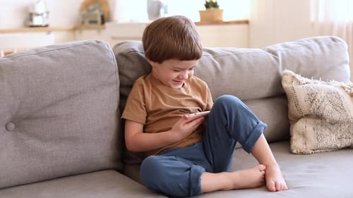Boy on Couch Uses Phone at Home