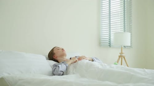 Young Woman Waking Up and Stretching in Bed