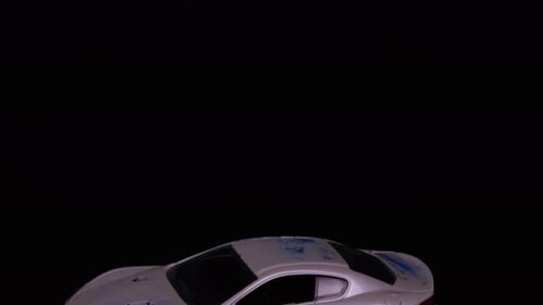 Silver Toy Car Rotating on Black Background