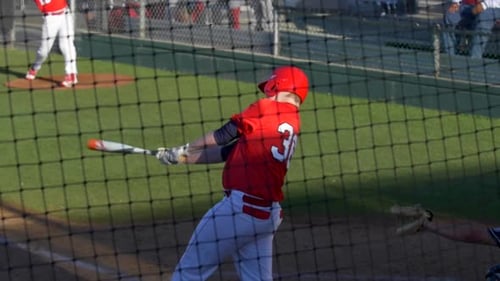 A baseball player batter makes a play at a game.