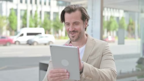 Man Using Tablet Celebrates Success in Urban Setting