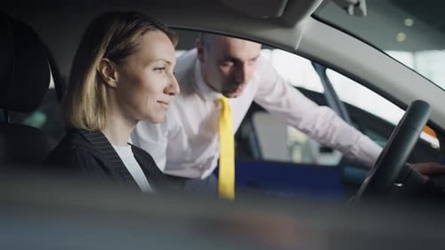 Woman Discussing Car with Salesman in Car Dealership