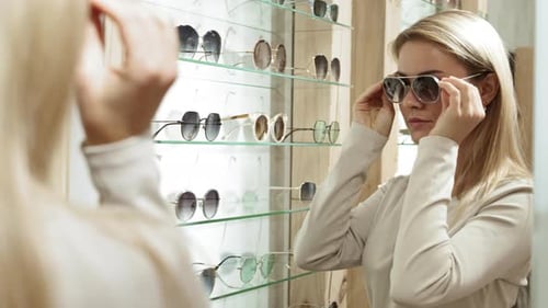 Beautiful Woman Choosing Sunglasses in Shop