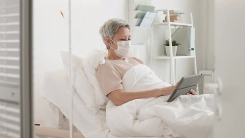 Woman Patient Using Tablet in Hospital Bed
