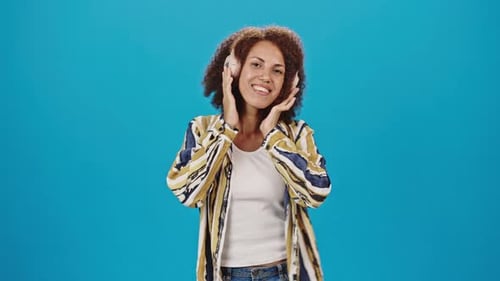 Woman Dancing to Music on Headphones in Studio