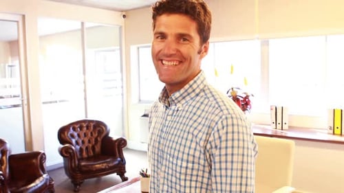 Smiling Man Standing in Bright Office