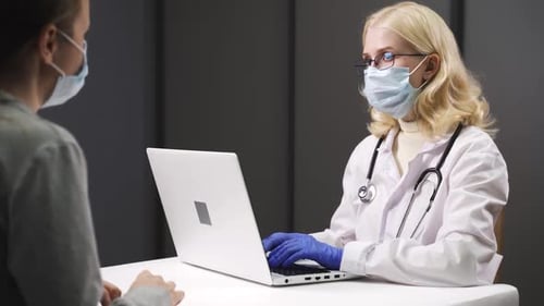 Doctor Typing on Laptop Talking to Patient