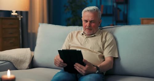 Man Using Tablet Device on Couch in Living Room