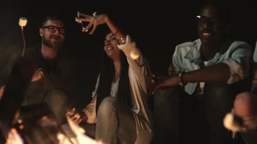Friends Laughing Around a Campfire at Night