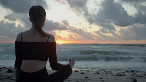 Woman Meditating on Peaceful Beach at Sunrise