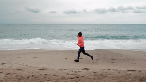 Running woman is jogging on beach