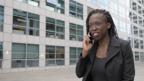 smiling succesful young black african businesswoman talking by phone in the city