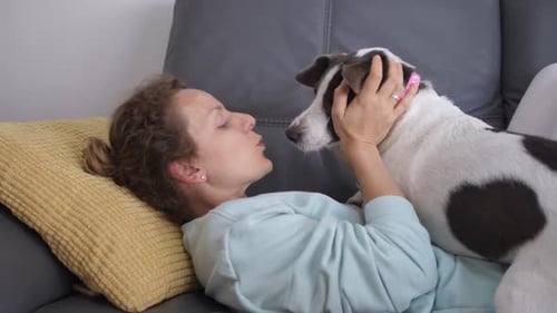 Happy Woman Playing with Cute Doggy Ears on Couch Having Fun Together