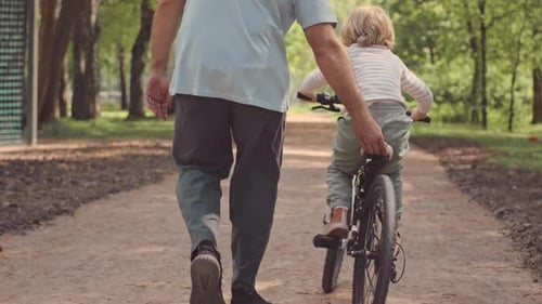 Father Teaching Son to Ride Bike in Park