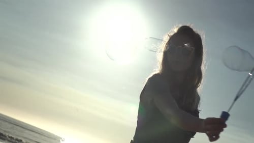 Young Woman Blowing Bubbles on a Sunny Beach