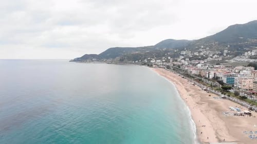 Beautiful empty coastline with sea waves, golden beach and residential buildings
