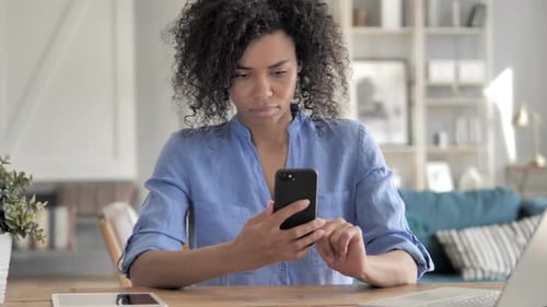 Woman Using Phone at Desk Indoors