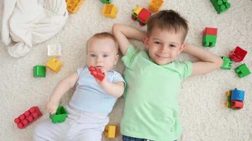 Two Brothers Relaxing on Carpet Surrounded by Toys